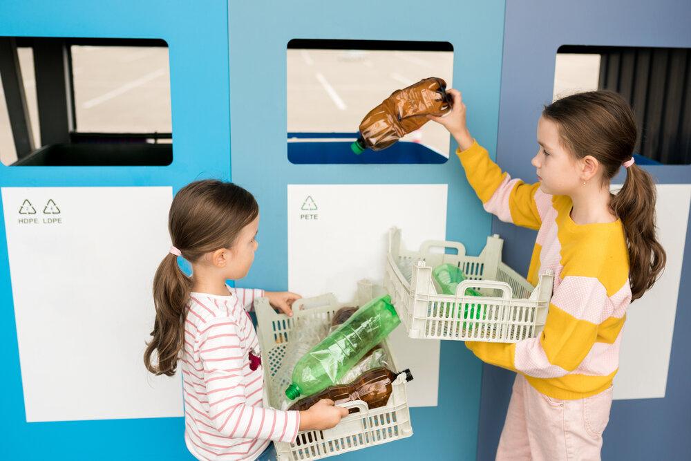 Two little girls recycling plastic bottles