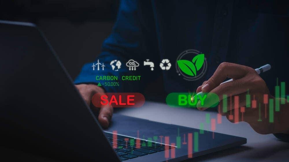Carbon credits buy and sel buttons in front of a man on a laptop