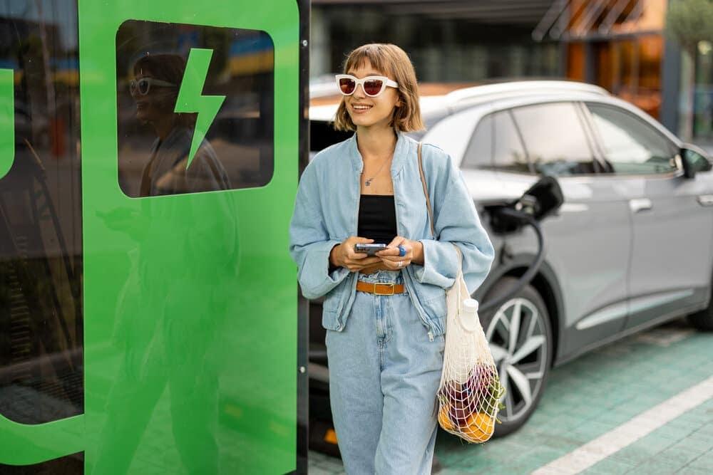 A woman stood next to an electric vehicle
