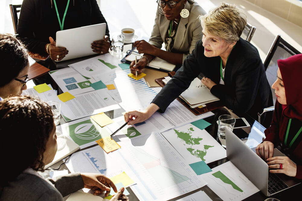 People having a table around a table with reports on it