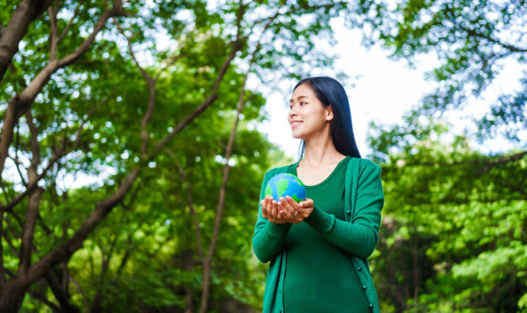 An woman holding a globe in green forest