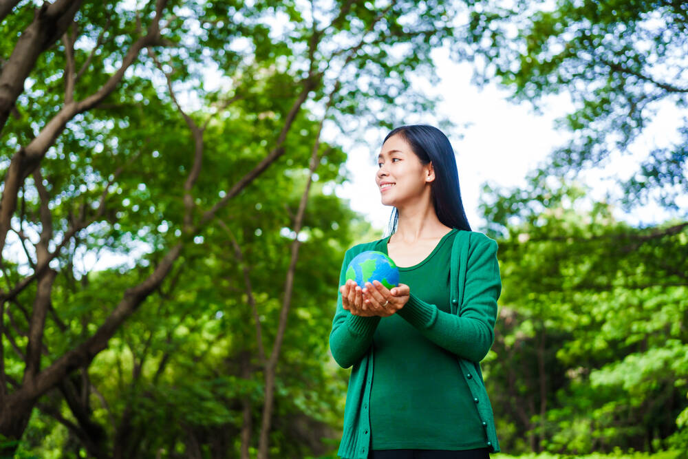 An woman holding a globe in green forest