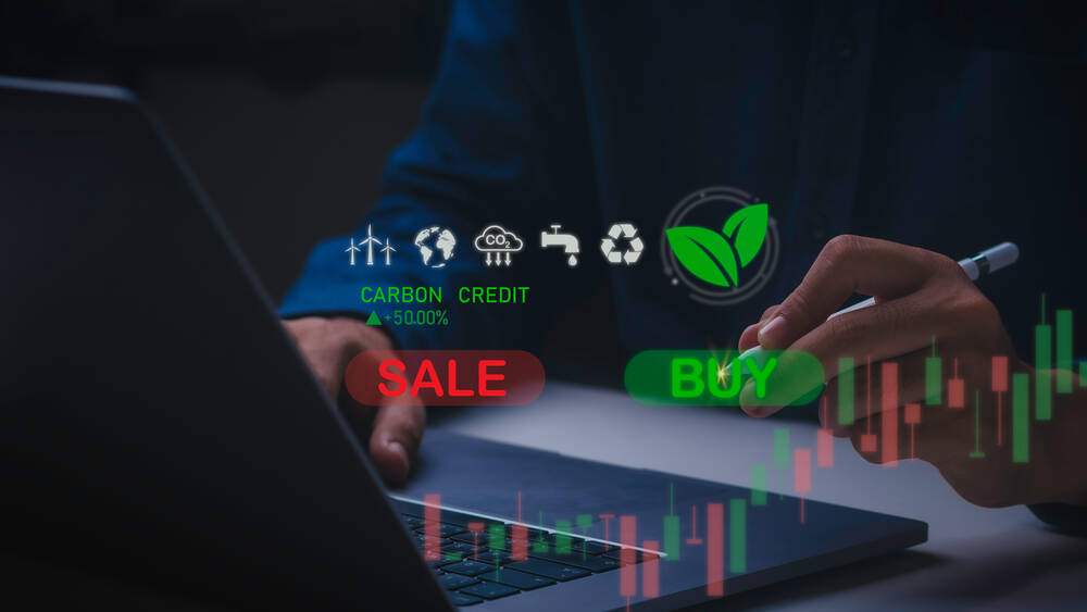 Carbon credits buy and sel buttons in front of a man on a laptop