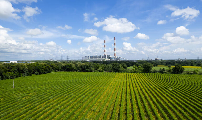 A green field with power plant in the background