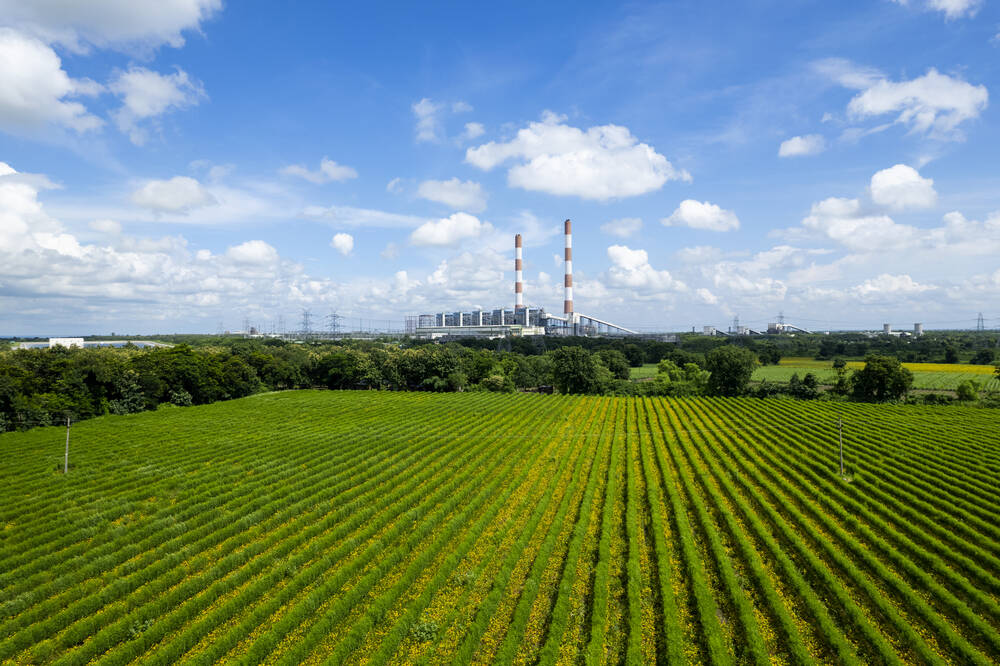 A green field with power plant in the background