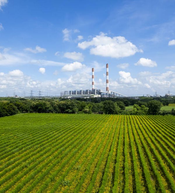 A green field with power plant in the background